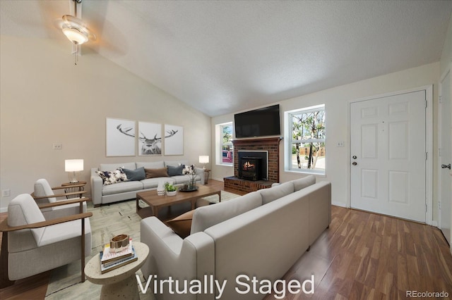 10832 W Powers Pl, Littleton, CO 80127 - living room with a fireplace, vaulted ceiling, wood finished floors, ceiling fan, and a textured ceiling