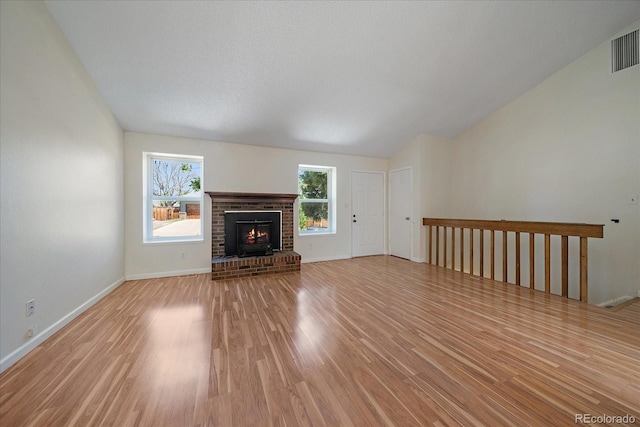 10832 W Powers Pl, Littleton, CO 80127 - unfurnished living room with light wood-style floors, healthy amount of natural light, vaulted ceiling, a fireplace, and baseboards