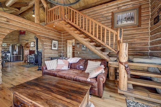 14475 N Yoder Rd, Calhan, CO 80808 - living room with rustic walls, a wood stove, a towering ceiling, wood finished floors, and stairs