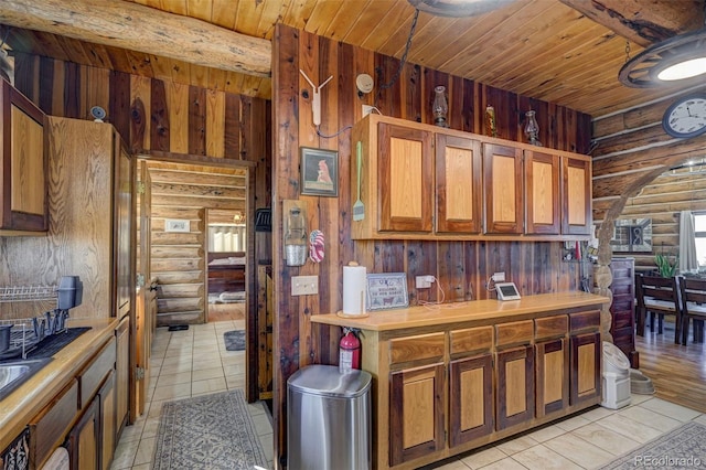 14475 N Yoder Rd, Calhan, CO 80808 - kitchen with rustic walls, wooden ceiling, light tile patterned floors, light countertops, and brown cabinetry