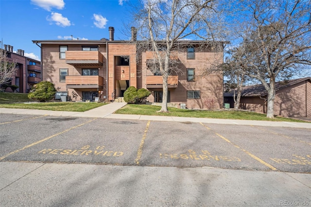 view of building exterior featuring uncovered parking and central AC