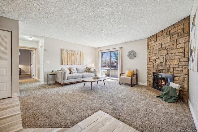 living area featuring light wood-type flooring, baseboards, a textured ceiling, and a fireplace