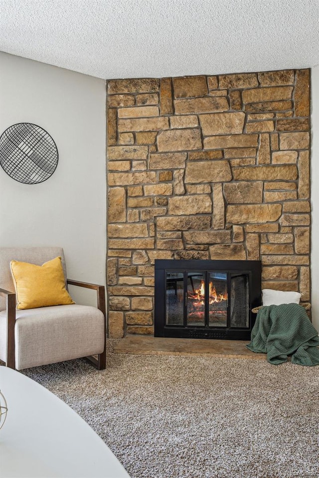 living area with a textured ceiling and a stone fireplace