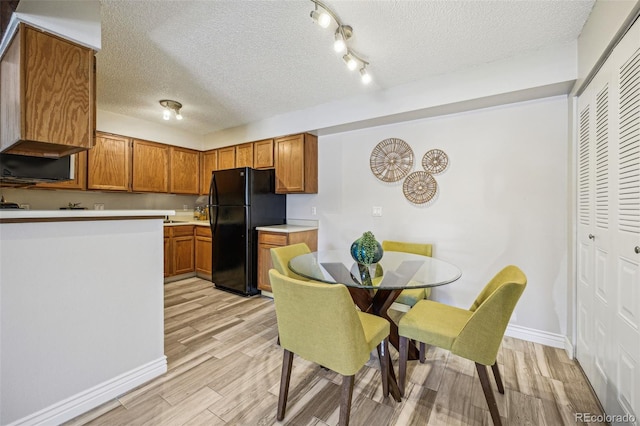 kitchen featuring brown cabinetry, light wood-type flooring, light countertops, and freestanding refrigerator