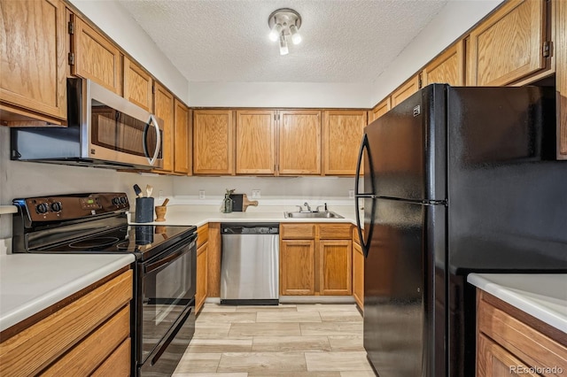 kitchen with a sink, brown cabinets, black appliances, and light countertops