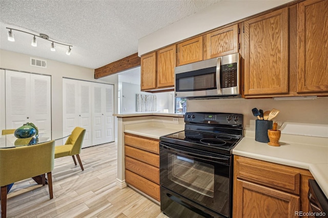 kitchen featuring visible vents, black appliances, light countertops, brown cabinets, and a textured ceiling