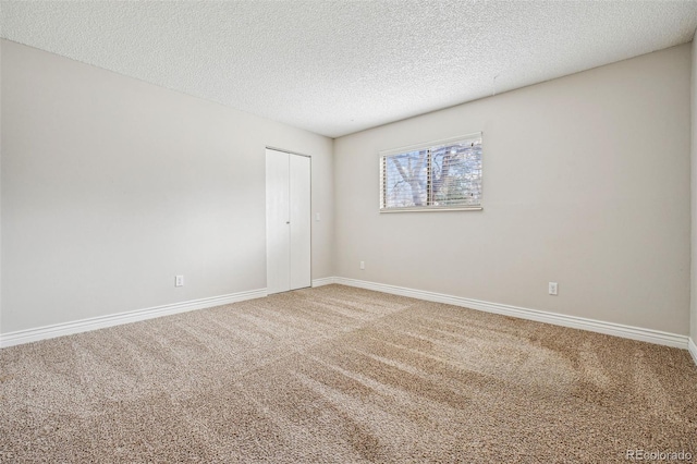 carpeted spare room with baseboards and a textured ceiling