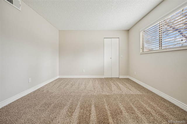 unfurnished bedroom with visible vents, carpet floors, a textured ceiling, and baseboards