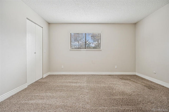 empty room featuring carpet flooring, baseboards, and a textured ceiling