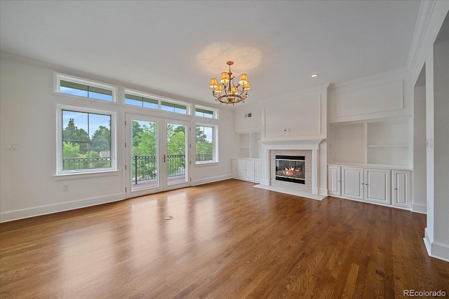 300 Hudson St Unit 203, Denver, CO 80220 - unfurnished living room featuring a chandelier, ornamental molding, built in features, a fireplace with flush hearth, and dark wood finished floors