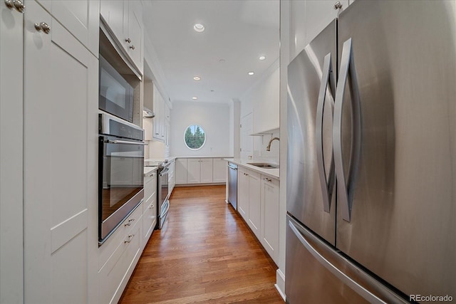 300 Hudson St Unit 203, Denver, CO 80220 - kitchen with appliances with stainless steel finishes, light wood-style flooring, white cabinetry, light countertops, and recessed lighting