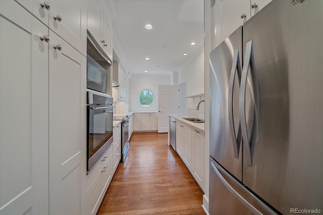300 Hudson St Unit 203, Denver, CO 80220 - kitchen featuring stainless steel appliances, light wood finished floors, white cabinetry, light countertops, and recessed lighting