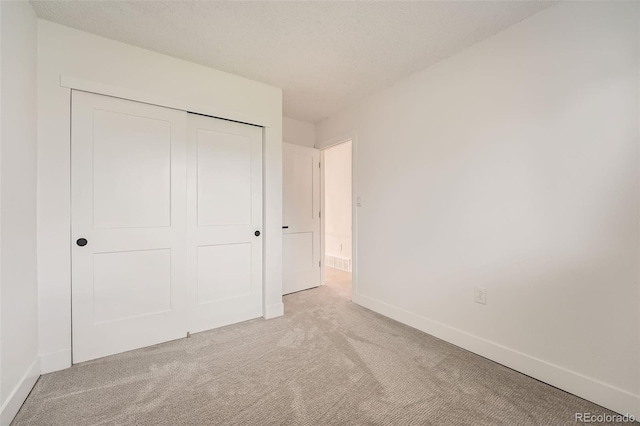 unfurnished bedroom featuring carpet floors, baseboards, and a closet