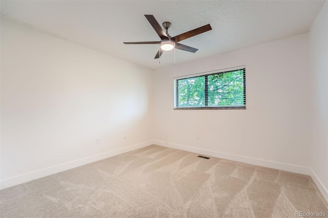 empty room with baseboards, a ceiling fan, and light colored carpet