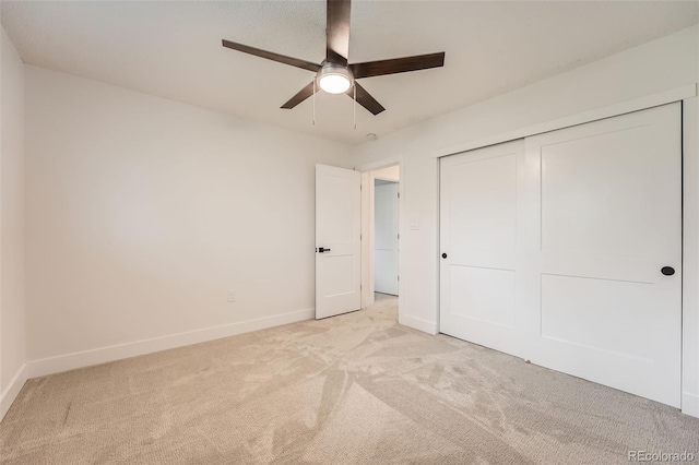 unfurnished bedroom featuring light carpet, baseboards, a closet, and a ceiling fan