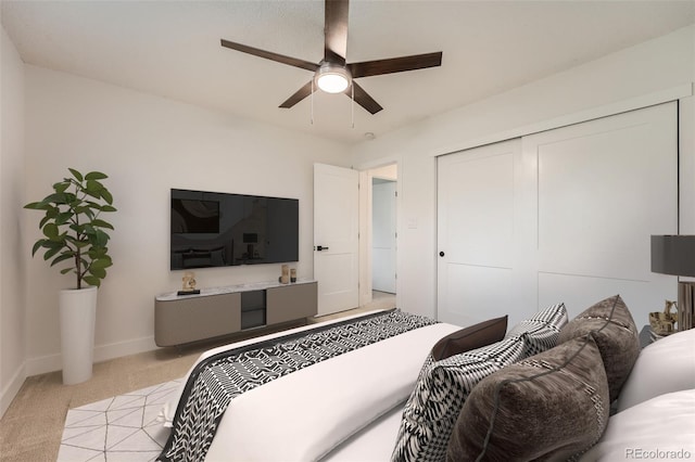 bedroom featuring light colored carpet, baseboards, a closet, and a ceiling fan