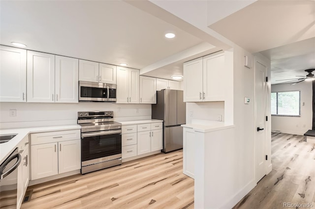 kitchen with appliances with stainless steel finishes, light wood finished floors, white cabinetry, light countertops, and recessed lighting