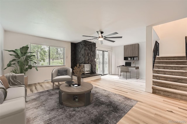 living area with plenty of natural light, stairway, wood finished floors, and ceiling fan
