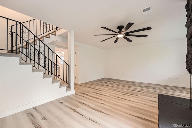 unfurnished living room with a ceiling fan, wood finished floors, stairs, and baseboards