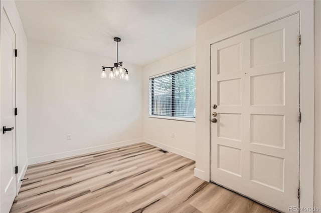 entryway with light wood-type flooring, a chandelier, and baseboards