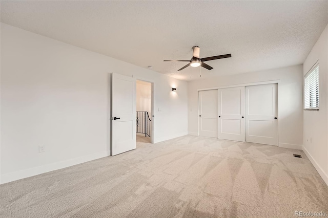 unfurnished bedroom with light carpet, baseboards, a ceiling fan, and a closet