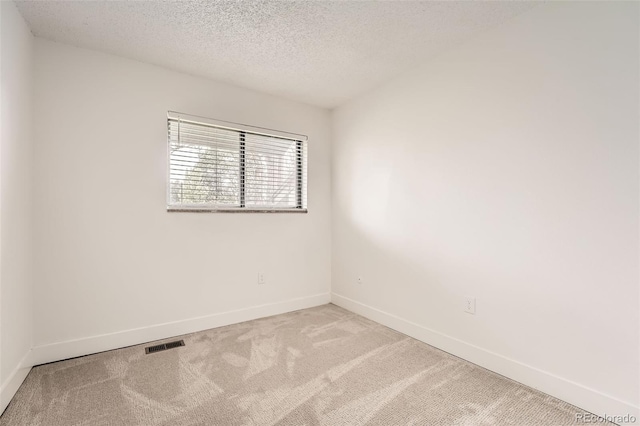 carpeted spare room featuring baseboards and a textured ceiling