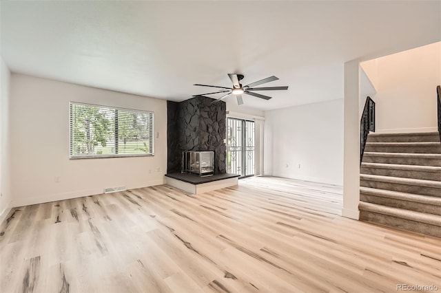 unfurnished living room with wood finished floors, stairs, ceiling fan, and healthy amount of natural light