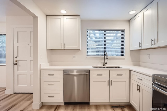kitchen with dishwasher, a sink, light wood-type flooring, stove, and light countertops