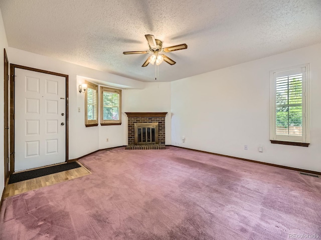 unfurnished living room with carpet flooring, plenty of natural light, a ceiling fan, a textured ceiling, and baseboards