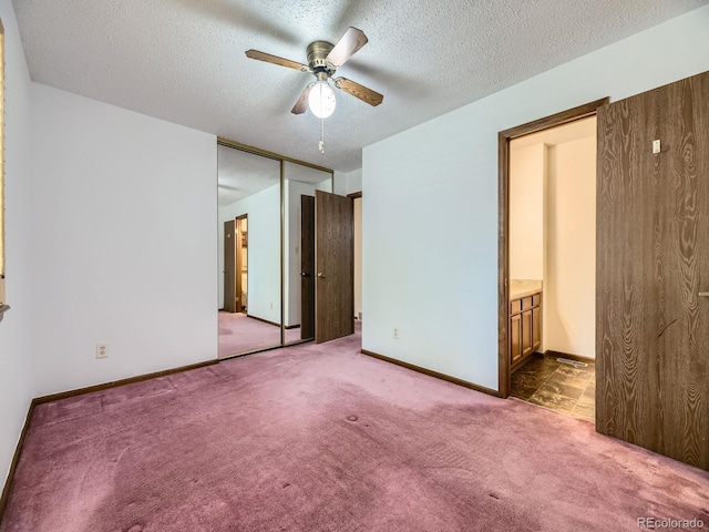 unfurnished bedroom with carpet, a textured ceiling, connected bathroom, a closet, and baseboards