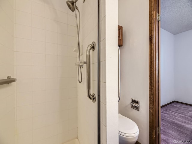 bathroom with a shower stall, toilet, and a textured ceiling