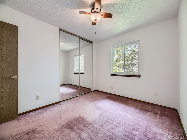 unfurnished bedroom featuring carpet floors, a textured ceiling, a closet, and baseboards