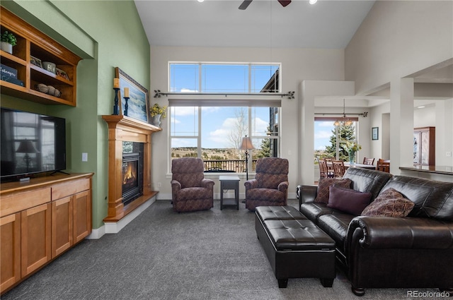 living area with a glass covered fireplace, a high ceiling, carpet flooring, and ceiling fan