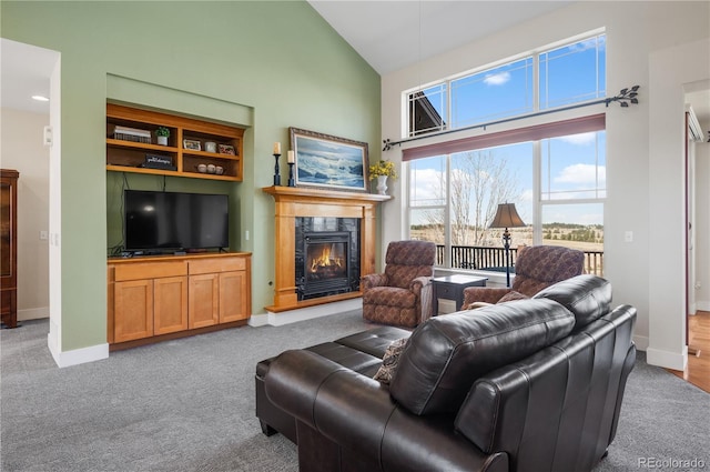 carpeted living room with high vaulted ceiling, a high end fireplace, and baseboards
