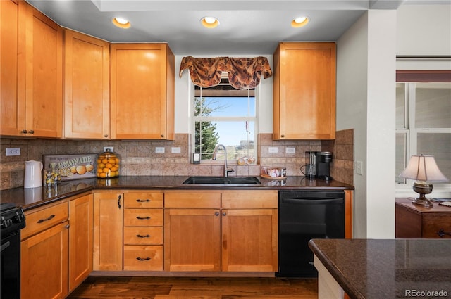 kitchen featuring dark wood finished floors, black appliances, decorative backsplash, and a sink