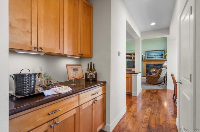 bar featuring a high end fireplace, baseboards, wood finished floors, and recessed lighting
