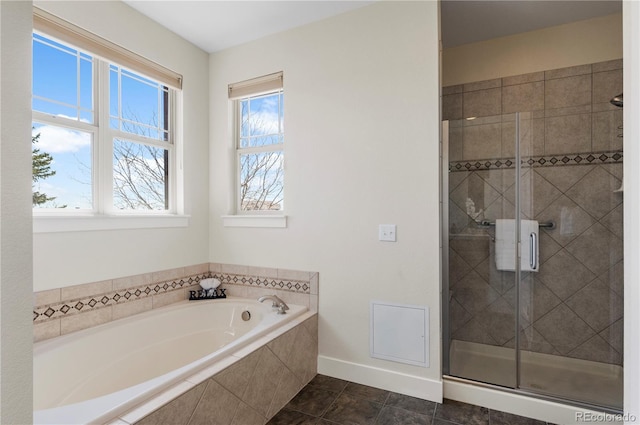 bathroom with baseboards, a bath, and a stall shower