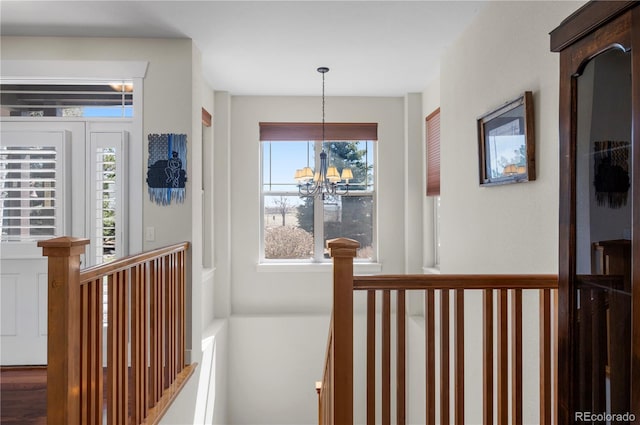 hallway with an upstairs landing and an inviting chandelier