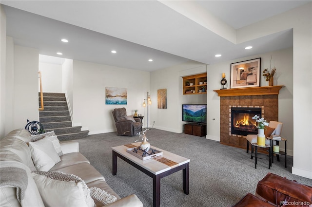 living area with a tiled fireplace, baseboards, carpet, recessed lighting, and stairway