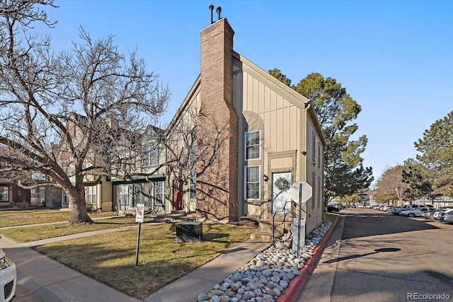 view of side of home with a chimney, a lawn, and board and batten siding