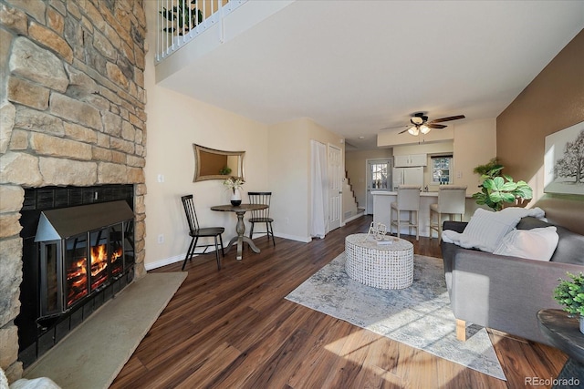 living room with ceiling fan, a fireplace, wood finished floors, and baseboards