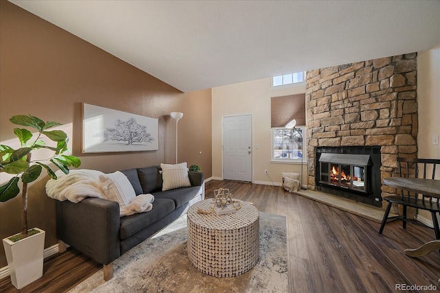 living area featuring visible vents, baseboards, wood finished floors, and a stone fireplace