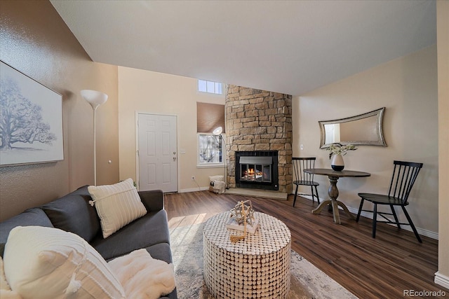 living room featuring a stone fireplace, wood finished floors, and baseboards