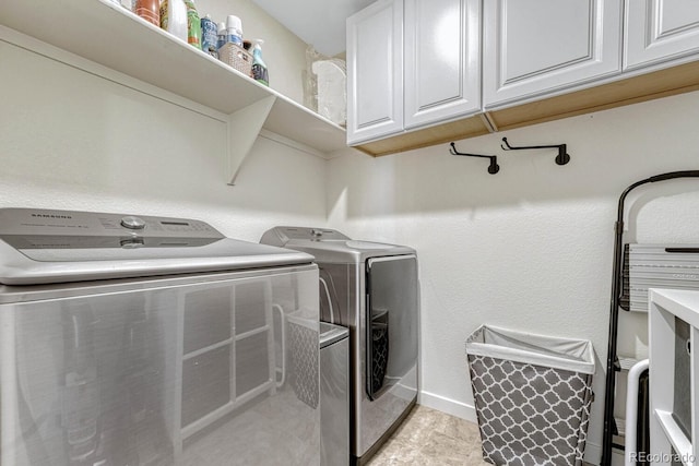 clothes washing area featuring cabinets and separate washer and dryer