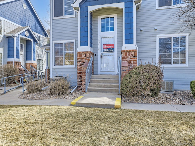 doorway to property featuring brick siding and a yard