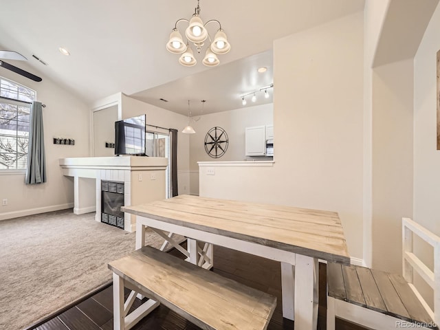 carpeted dining space with lofted ceiling, a tile fireplace, baseboards, and a chandelier