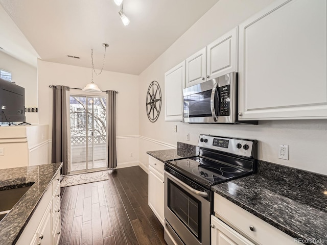 kitchen with white cabinetry, dark wood-type flooring, appliances with stainless steel finishes, and dark stone counters