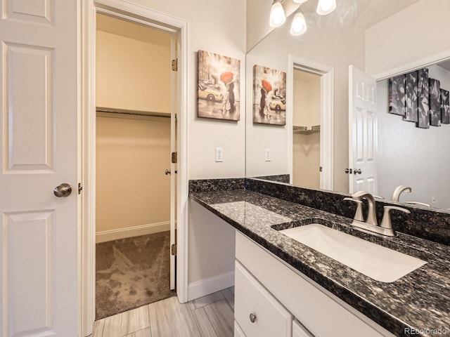 bathroom featuring vanity, a walk in closet, and baseboards