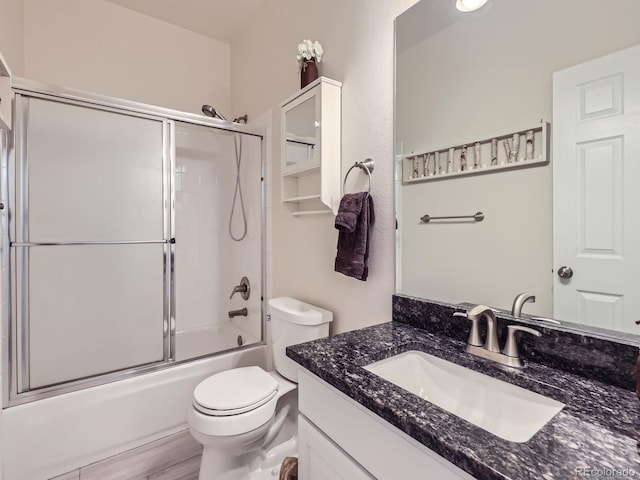 bathroom with vanity, toilet, and shower / bath combination with glass door