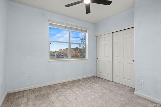 unfurnished bedroom featuring ceiling fan, a closet, and light carpet